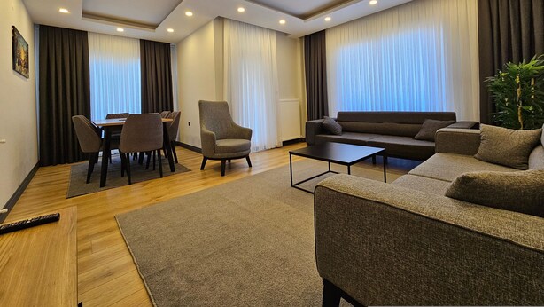 A modern living room with a sofa, armchair, and dining table.