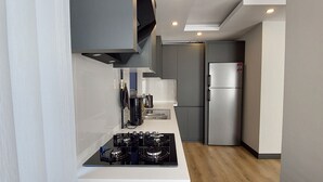 Eine moderne Küche mit Gasherd, Edelstahlkühlschrank und grauen Schränken.