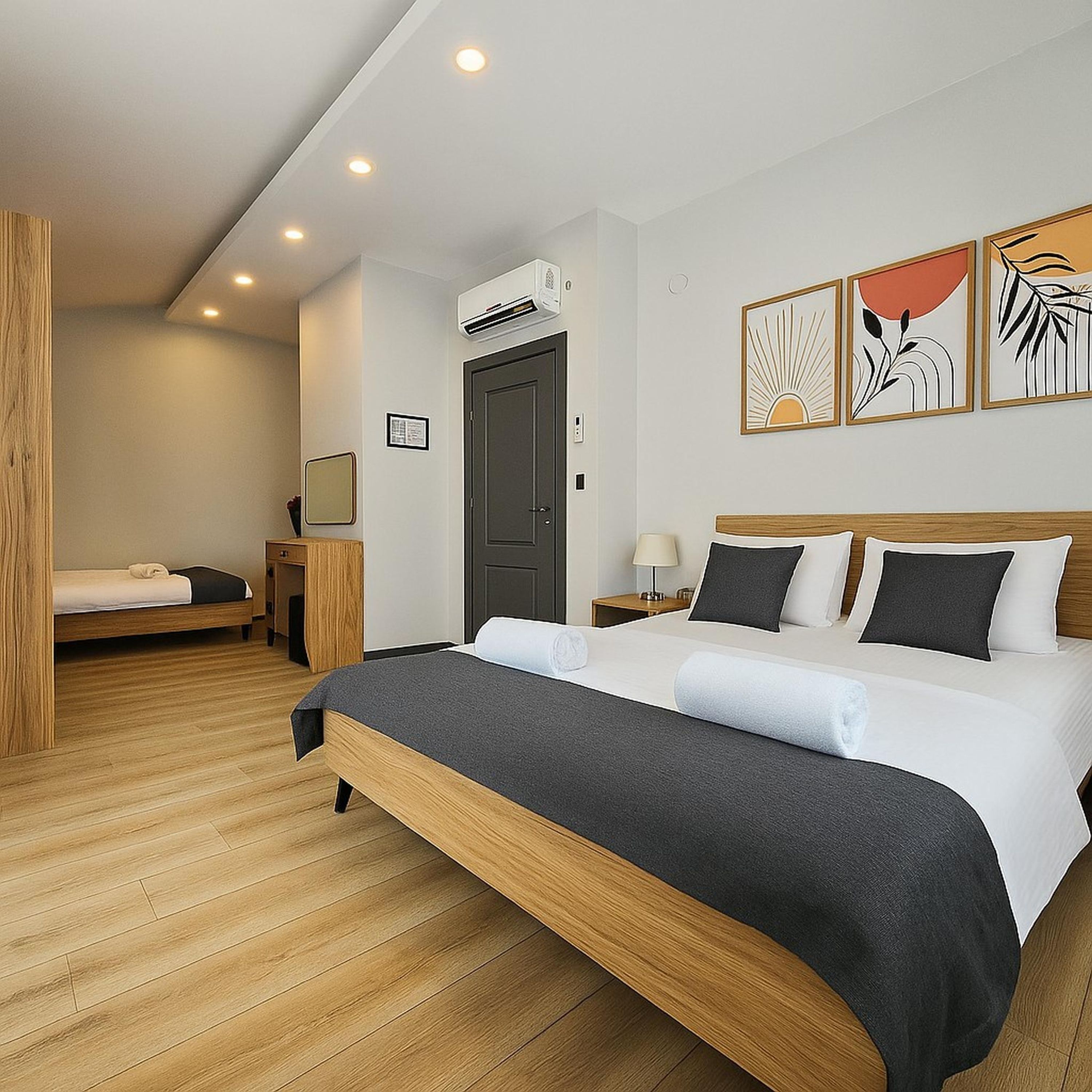 Une chambre d’hôtel avec un grand lit, un lit plus petit, un appareil de climatisation et des œuvres d’art accrochées au mur.