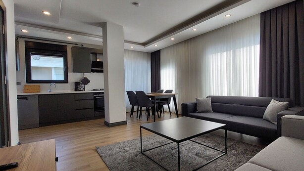 Ein modernes Wohnzimmer mit einer Couch, einem Couchtisch und einem Essbereich mit Stühlen und einem Tisch.