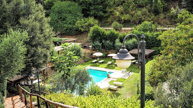 Un espace piscine doté d’une terrasse en bois, de chaises longues et d’une pergola.