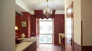 A hallway with a chandelier, a window with curtains, a door, and a table with a chair. - Imperial Guest House - Full Apartment no kitchen (Roma)