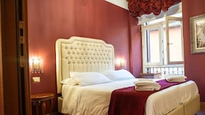 A bedroom with a large bed, a nightstand, a window with a view, and a red curtain. - Imperial Guest House - Full Apartment no kitchen (Roma)