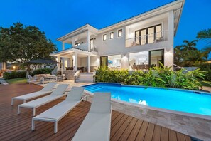 A modern two-story house with a swimming pool, outdoor seating, and a well-maintained garden.