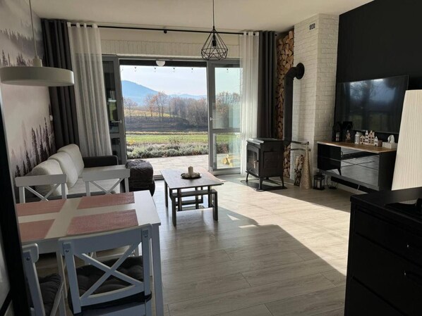 A modern living room with a sofa, dining table, and a fireplace. - Enchanted Hill House of the Beskids (Porabka)