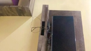 Une pièce avec un plancher en bois, un panneau de séparation violet et un meuble noir.