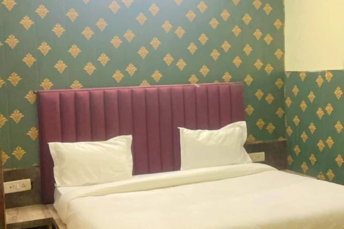 A bedroom with a bed, a ceiling fan, and patterned wallpaper.