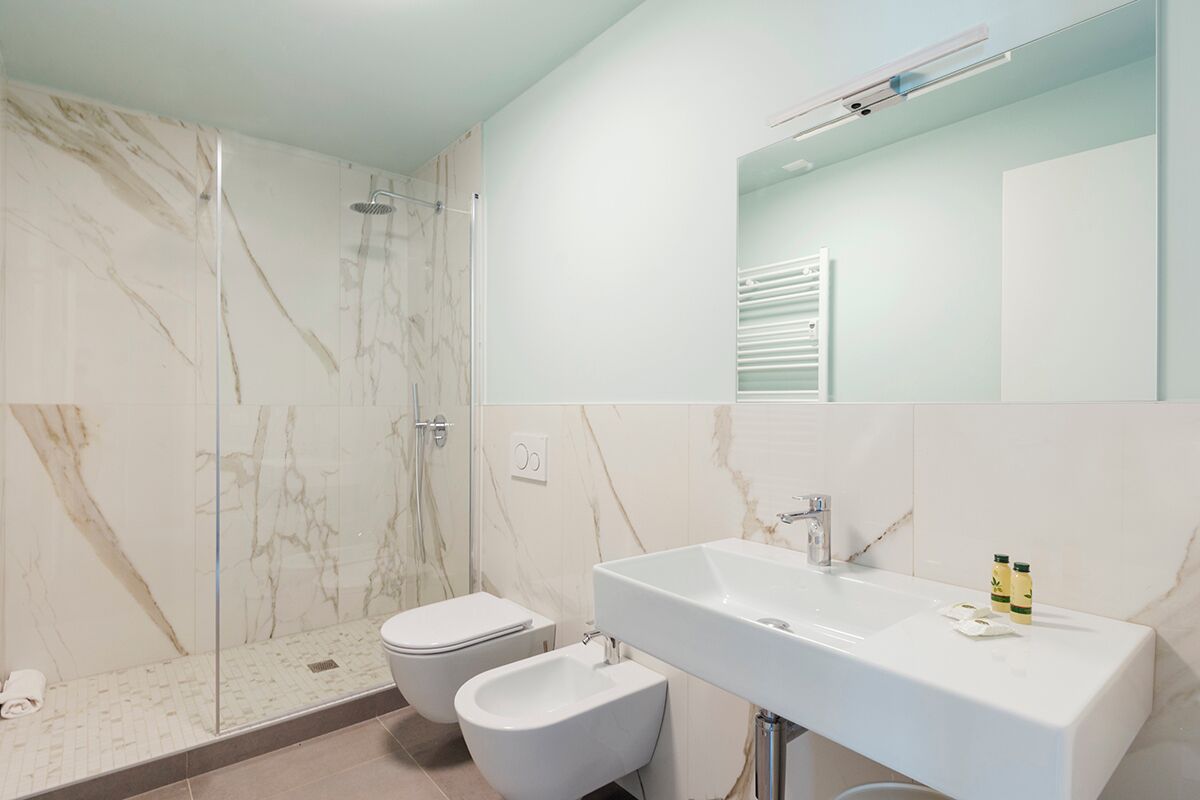 A modern bathroom with a shower, toilet, bidet, and a large sink.