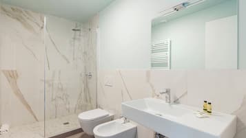 A modern bathroom with a shower, toilet, bidet, and a large sink.