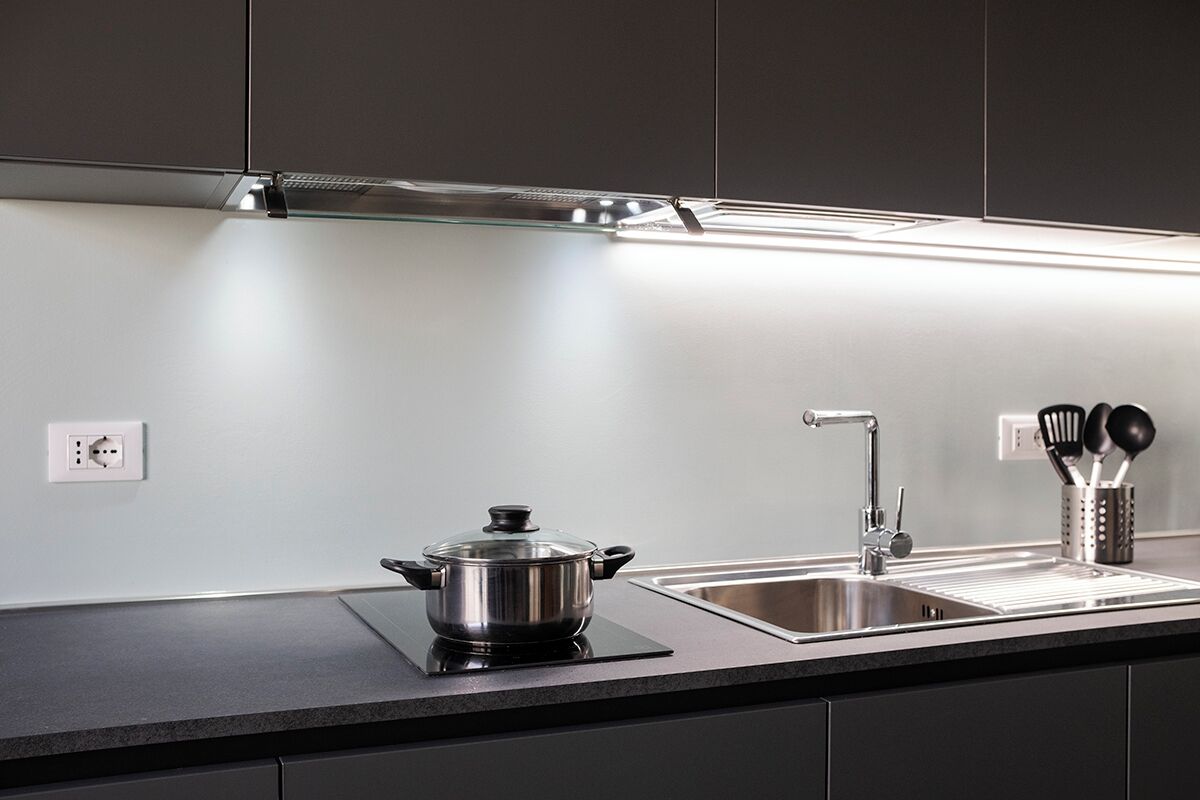 Una cucina moderna con piano cottura integrato, lavello in acciaio inossidabile e una pentola sul bancone.