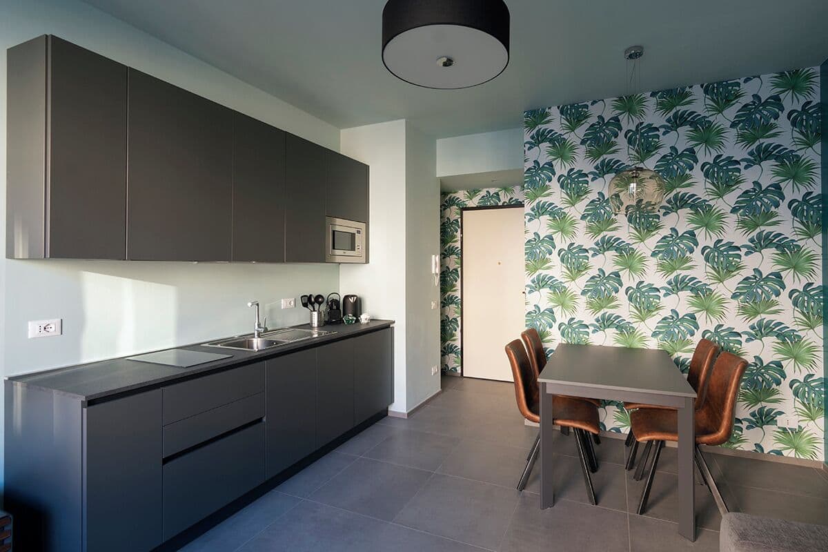 A modern kitchen with dark cabinets, a built-in microwave, and a dining area with a table and chairs.