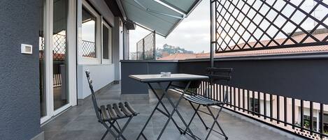 Un balcon avec une table et des chaises, un filet de protection et une vue sur les bâtiments.