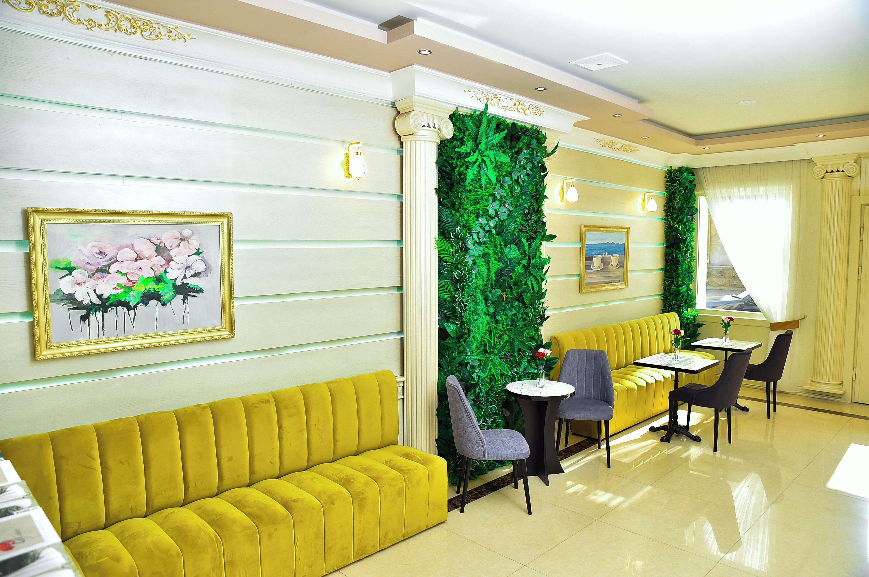 Un sofá amarillo, una pared verde y una mesa con sillas en el vestíbulo de un hotel.