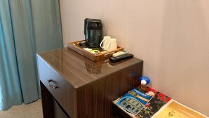 A wooden bedside table with a coffee maker, mugs, a remote control, and a magazine. - Karat Inn Boutique Hotel (Baku)