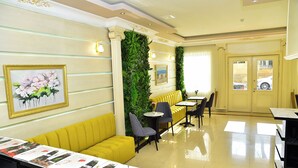 A hotel lobby with yellow seating, a reception desk, and a green wall with plants. - Karat Inn Boutique Hotel (Baku)