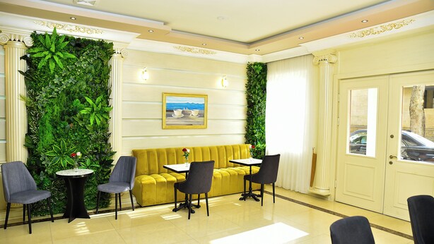 A lobby with a yellow sofa, two round tables, and four chairs. - Karat Inn Boutique Hotel (Baku)