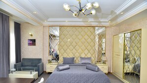A hotel room with a large bed, a sofa, a dining table, and a mirror. - Karat Inn Boutique Hotel (Baku)