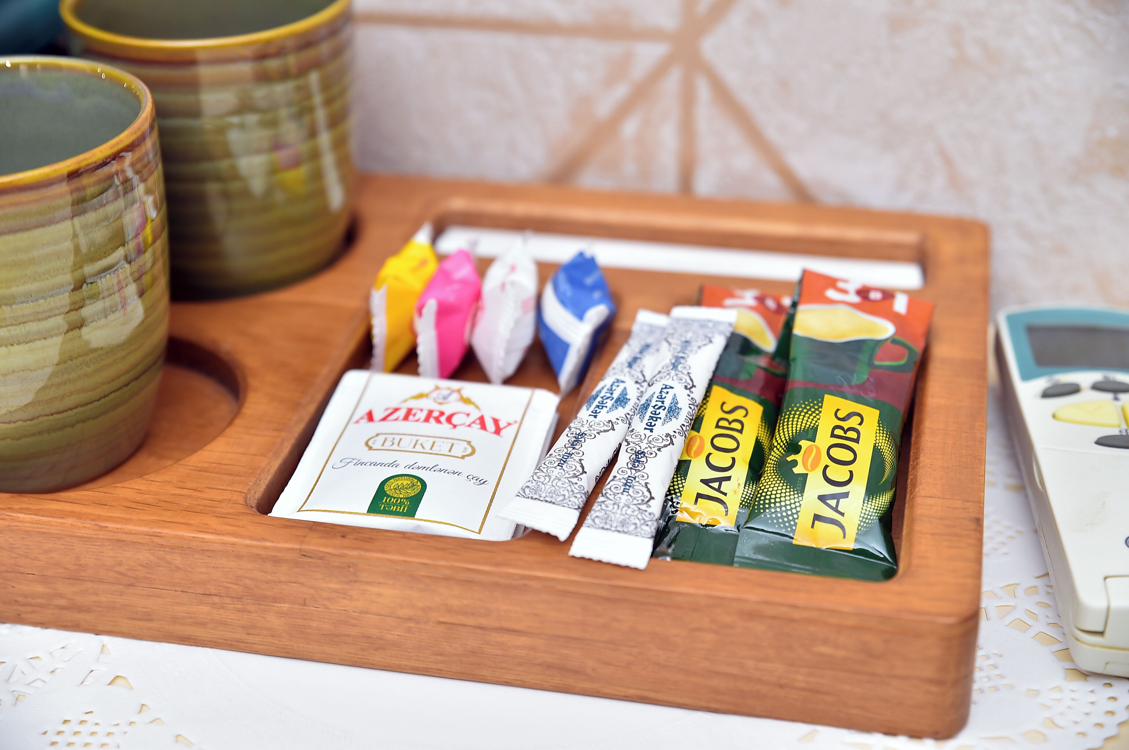 A wooden tray with a packet of ZERÇAY BUKEŞ, a pack of Jacobs, and two ceramic cups.