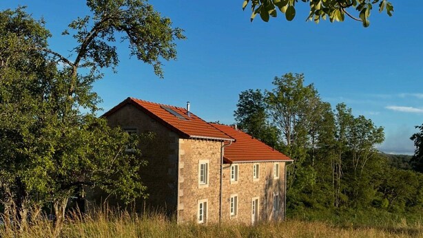 Ein Gebäude aus Stein mit rotem Dach, umgeben von Bäumen und Gras.