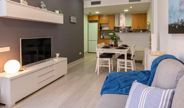 A modern living room with a TV, sofa, and dining area.