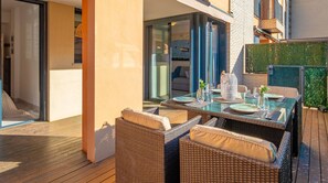 An outdoor dining area with wicker furniture, a glass table, and a view of the sea.