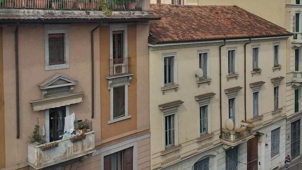 Un edificio de varios pisos con balcones, techo plano y antenas parabólicas.