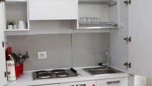 Una cocina moderna con armarios blancos, una estufa y un lavabo. Hay un florero con flores sobre la mesa.