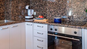 A kitchen with granite countertops, stainless steel appliances, a coffee machine, and a blue pot on the stove.