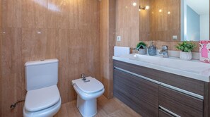Ein modernes Badezimmer mit Toilette, Bidet und einem Waschtisch mit Spiegel und Waschbecken.