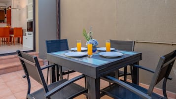 An outdoor dining area with a table set for four, surrounded by chairs.