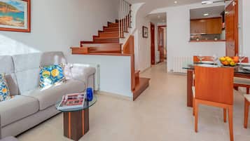 Una sala moderna con un sofá, una mesa de centro y una escalera que conduce a una zona de cocina.