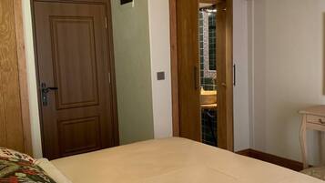 A bedroom with a bed, wooden ceiling, and a door leading to another room.