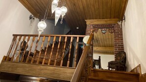 A wooden staircase with a chandelier, a brick wall, and a mirror reflecting the staircase. - Sofia Konaklama (Istanbul)