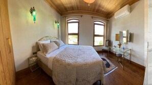 A bedroom with a bed, bedside table, lamp, mirror, and a desk with a chair. - Sofia Konaklama (Istanbul)