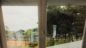 A room with a view through a window, a radiator, a small table with a vase, and a chair. - Rose de Picardie in BAIE DE SOMME 3 minutes from the beach and shops (Cayeux-sur-Mer)