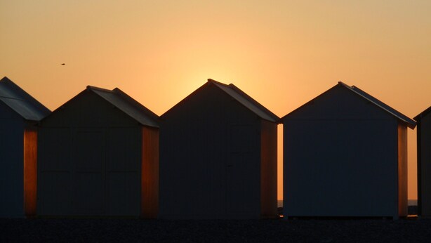 A row of beach huts with a sunset in the background. - Rose de Picardie in BAIE DE SOMME 3 minutes from the beach and shops (Cayeux-sur-Mer)