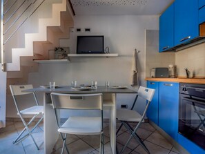 A modern kitchen with a dining table, chairs, and blue cabinets. - Pleasant loft studio near beaches and town center (Menton)