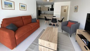Ein modernes Wohnzimmer mit Sofa, Sessel, Couchtisch und TV-Schrank.