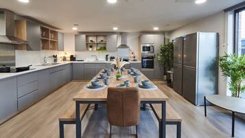 A modern kitchen with grey cabinets, a wooden dining table set with blue dishes, and a large window providing natural light.