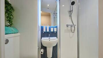 Une salle de bain moderne avec une douche à parois de verre, un lavabo blanc et un mur d’accent bleu.