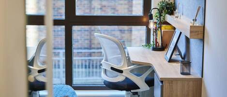 A modern office chair with a mesh backrest and a wooden desk with a small plant and a picture frame.