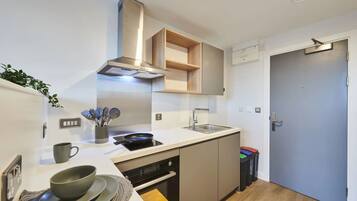 A modern kitchen with a built-in stove, sink, and overhead ventilation hood.