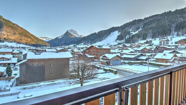 A snow-covered mountain town with wooden buildings and a prominent mountain peak in the background. - 3-room apartment with southwest view and wifi in Morzine (Morzine)