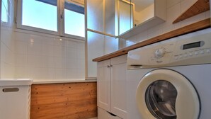 A compact kitchen with a built-in washing machine, wooden cabinetry, and a window providing natural light. - 3-room apartment with southwest view and wifi in Morzine (Morzine)