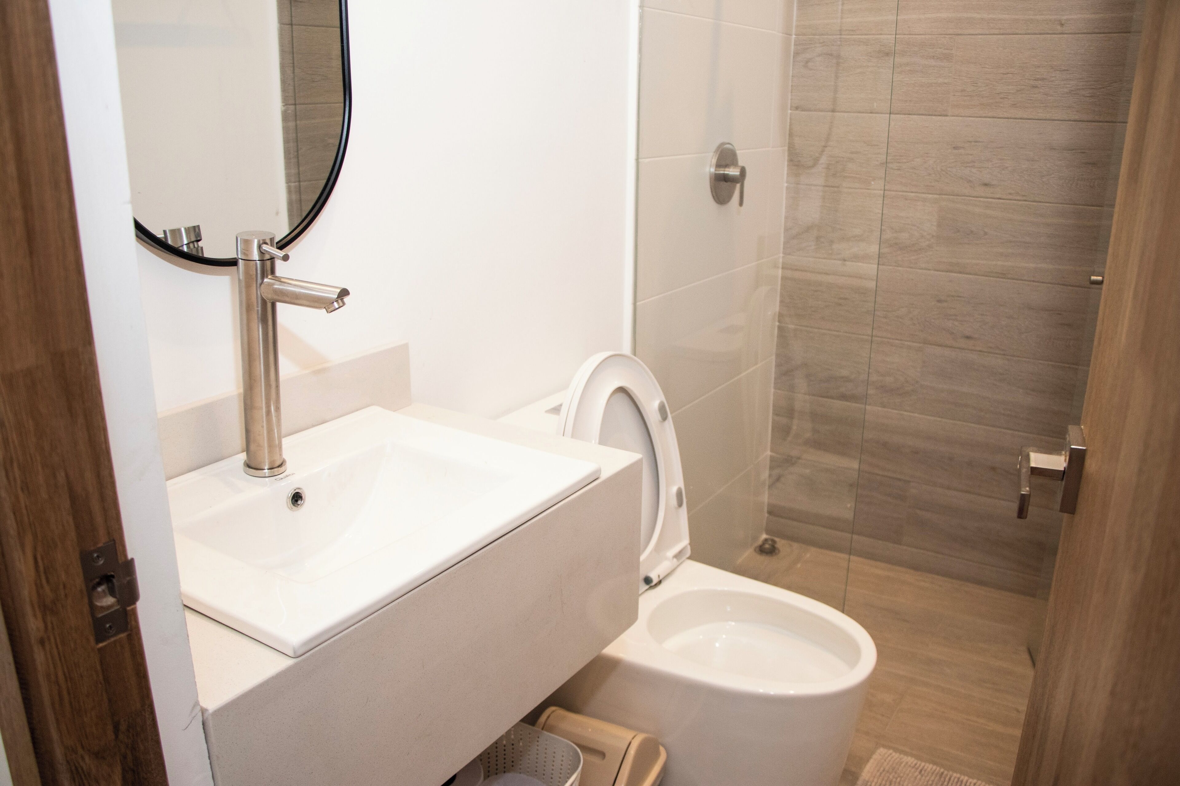 Ein modernes Badezimmer mit einem weißen Waschbecken, einer Toilette und einer Duschkabine aus Glas.
