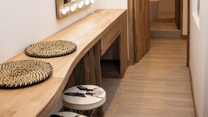 A hallway with a vanity area featuring a mirror with lights, a wooden bench, and stools. - zenia (Medellín)