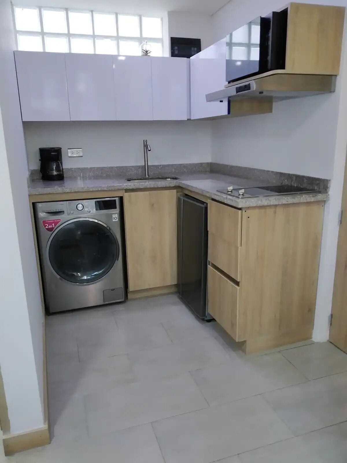 A compact kitchen with a washing machine, a sink, and wooden cabinets.