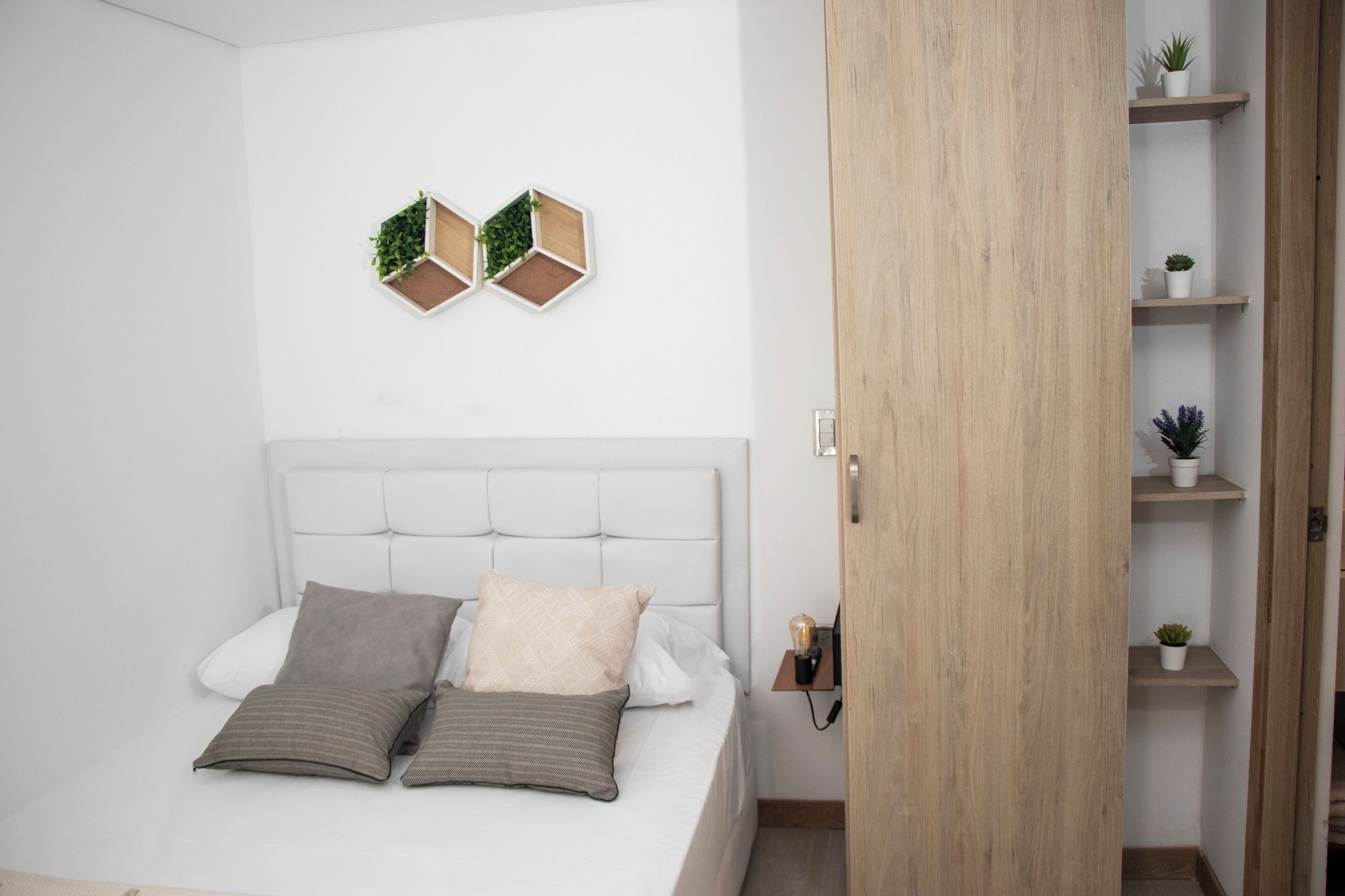 Un dormitorio con cama, dos adornos hexagonales en la pared y un armario de madera con estantes.