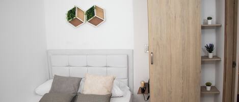 Un dormitorio con cama, dos adornos hexagonales en la pared y un armario de madera con estantes.
