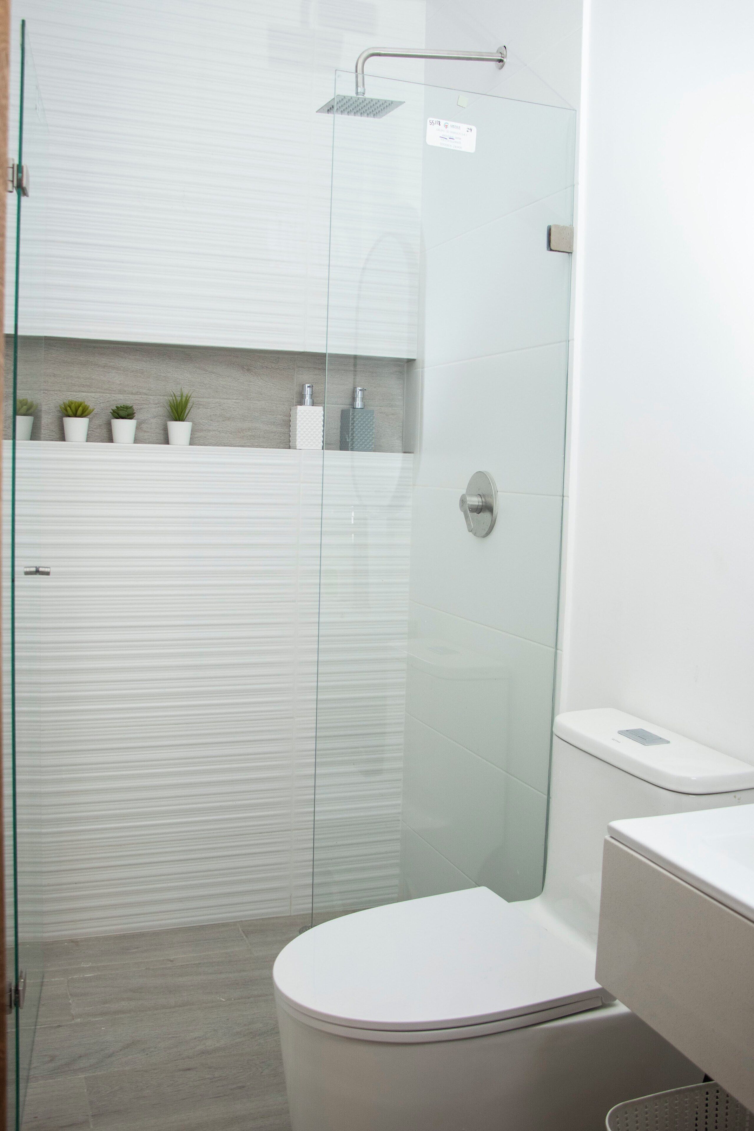 Een moderne badkamer met een douchecabine van glas, een toilet en een wastafel.